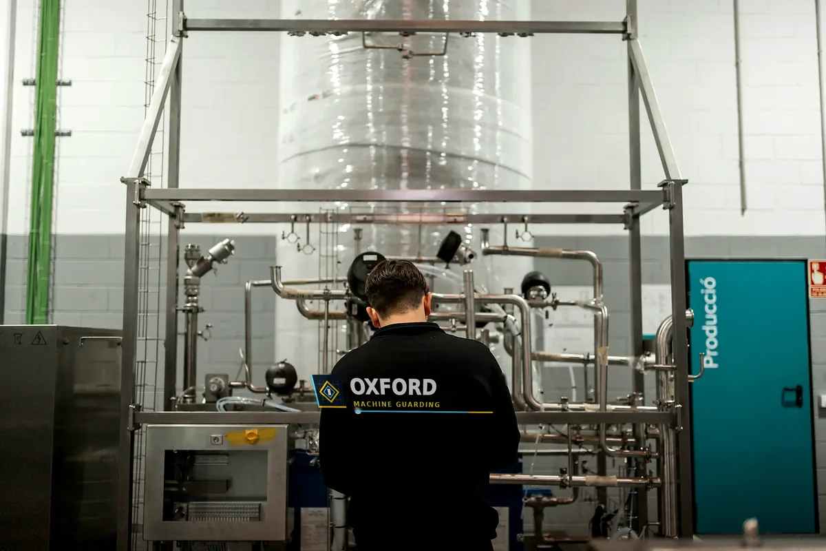 Person facing stainless steel process equipment in an industrial facility.